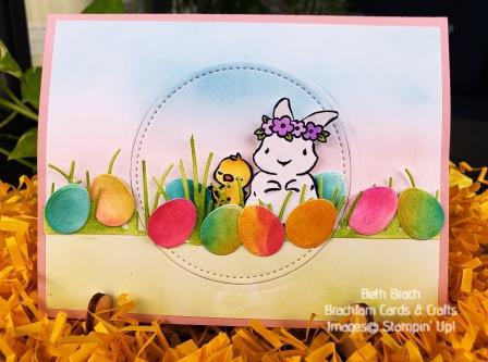 Easter eggs strewn across a field of grass watched over by a little chick and bunny.